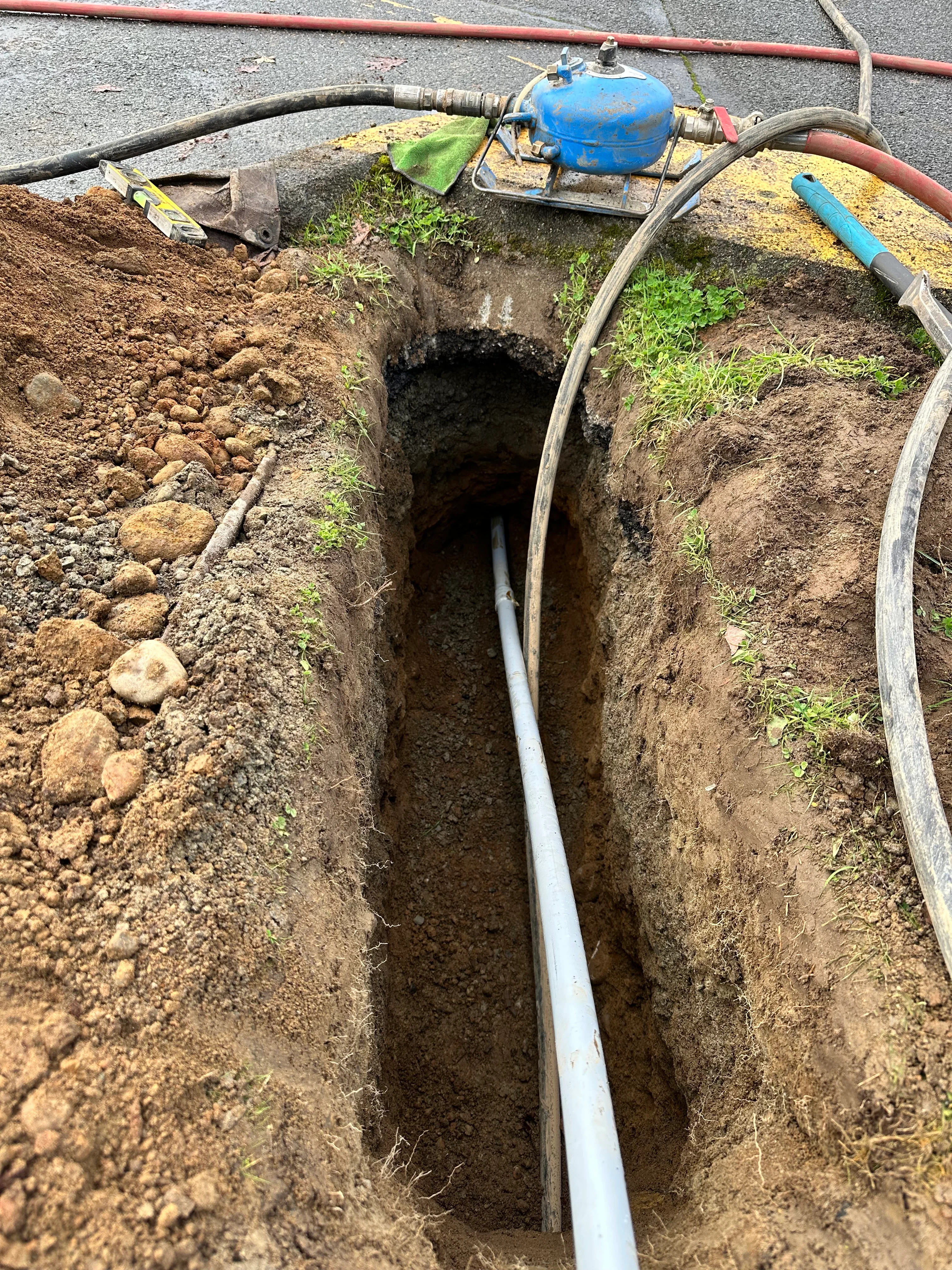 Underground utility line installation in excavated trench with PVC pipe and pressure tank