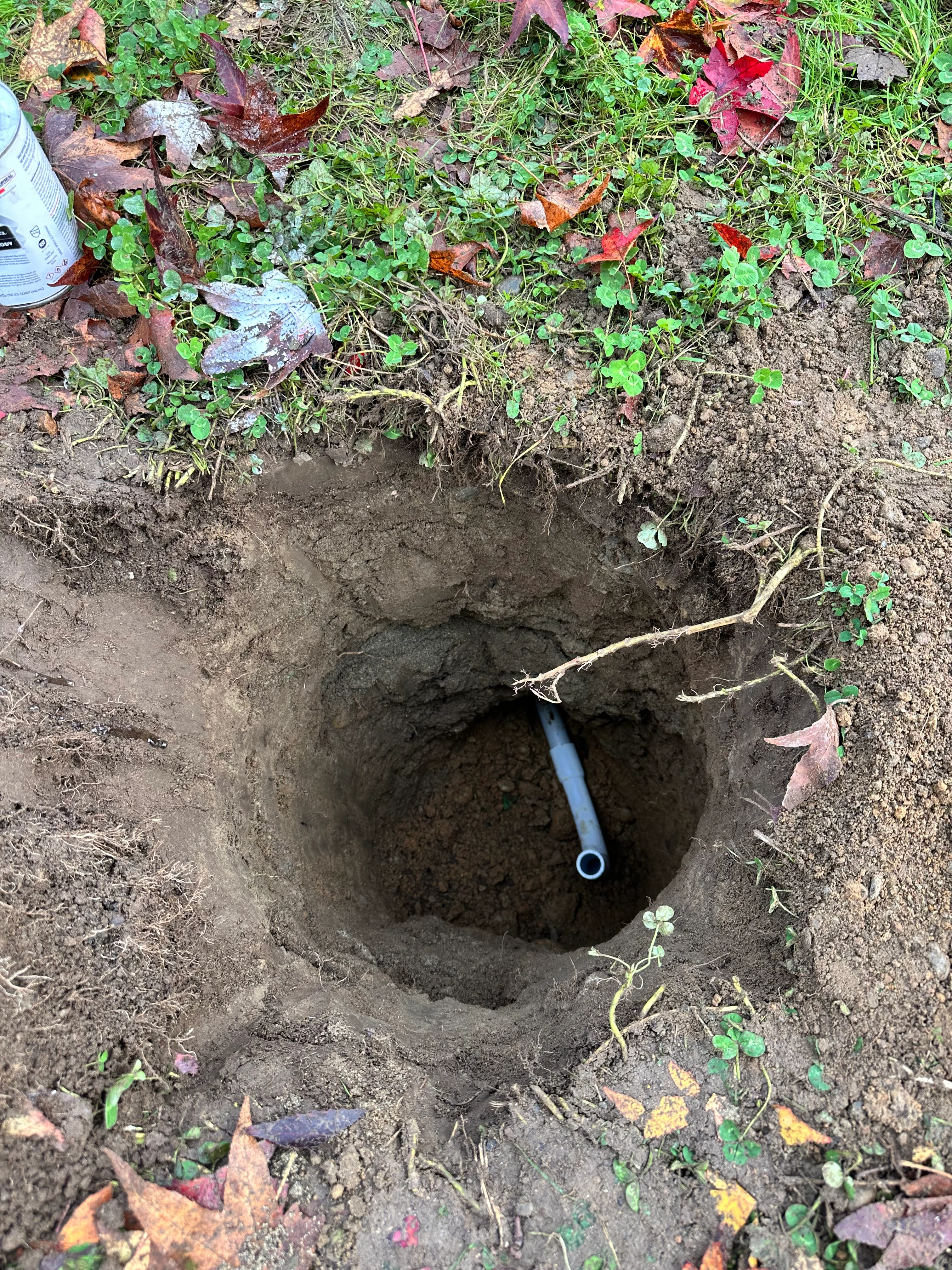 Underground utility pipe installation in excavated trench with blue PVC line visible